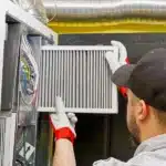 HVAC technician replacing a dirty air filter in a furnace cabinet